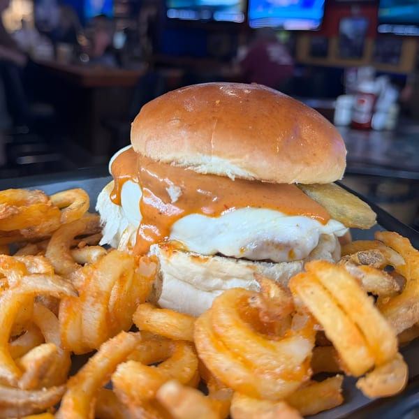 Crawford's Corner Bar & Kitchen's fried chicken sandwich with sauce and curly fries.
