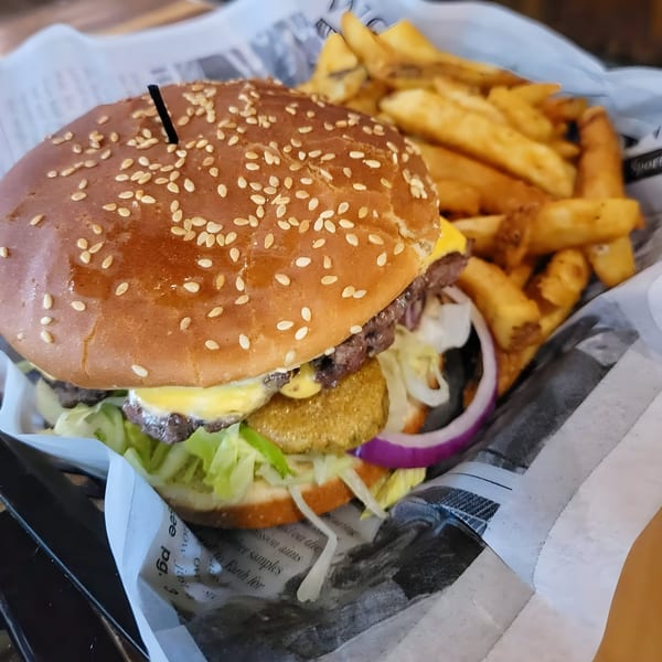 A Crawford's Corner burger with cheese, lettuce, onion, and pickles, served with fries.